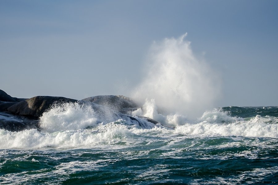 Stormiga vågor som piskar upp på klippor